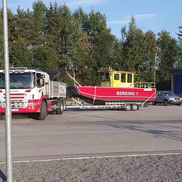 Gull og rød berginsbåt blir fraktet på henger